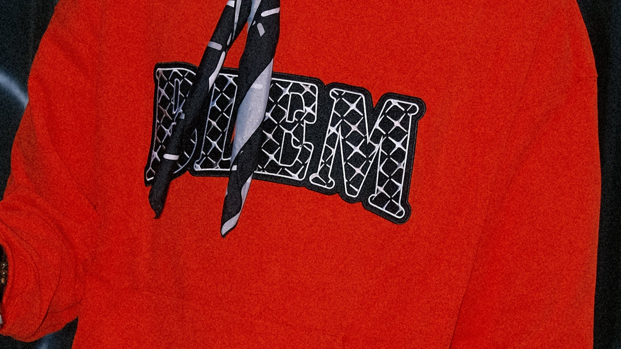 man wearing a red blem hoodie with a black and white bandana around his neck